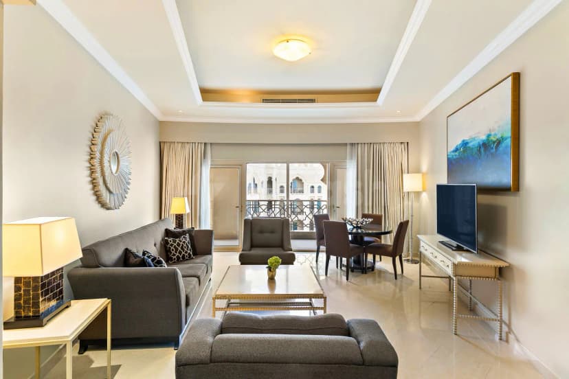 Meeting room at Al Hamra Residence in Ras Al-Khaimah featuring a grey sofa, abstract blue painting, and balcony