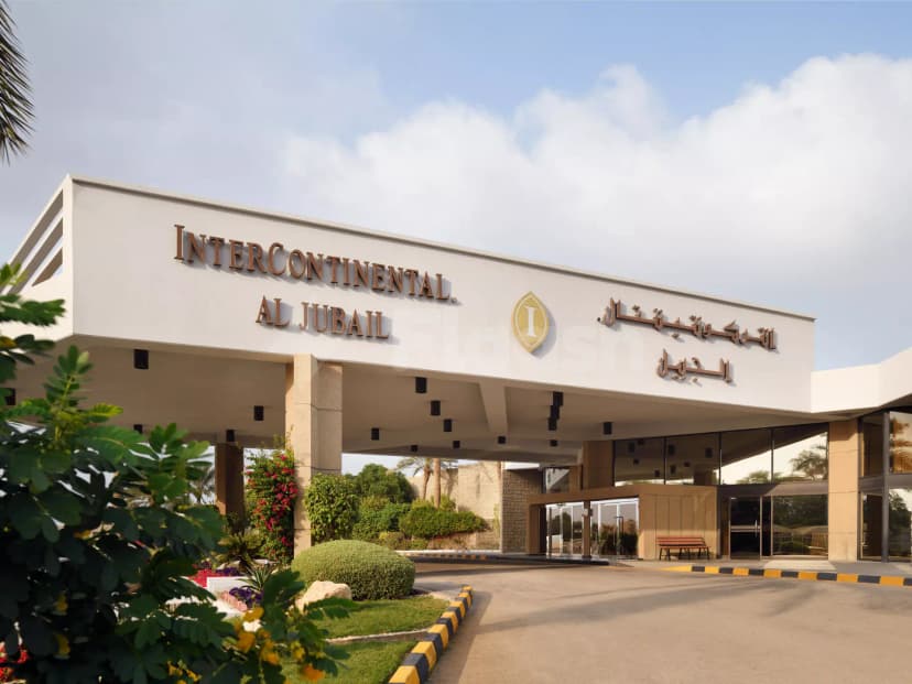 Hotel facade of InterContinental Al Jubail featuring white overhang with English and Arabic signage, beige stone columns
