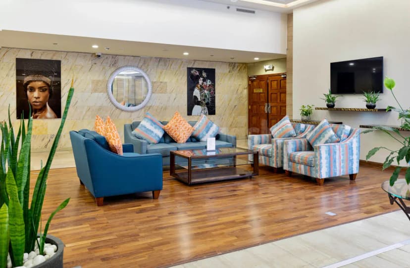 Entrance hall at Treffen House Doha featuring a marble wall with artwork and a round mirror, modern lounge