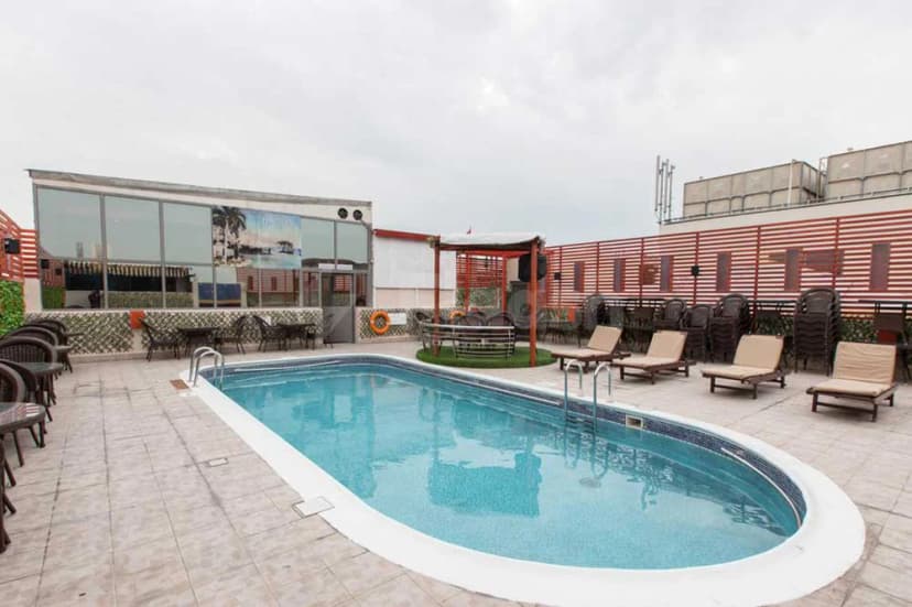 Rooftop swimming pool at Grand Central Hotel Dubai with white tiled edge, metal ladder, beige lounge chairs