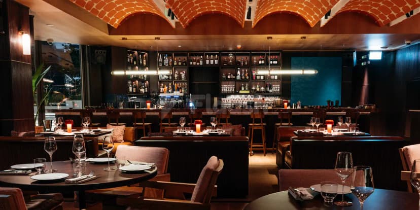 Restaurant interior at Chez Wam in Dubai featuring a red brick arched ceiling and a backlit bar