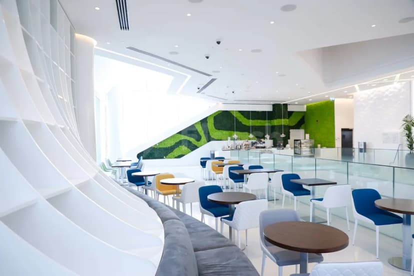 Restaurant at Sustainability & Innovation Centre Dubai featuring a curved white shelving unit and a green living wall behind