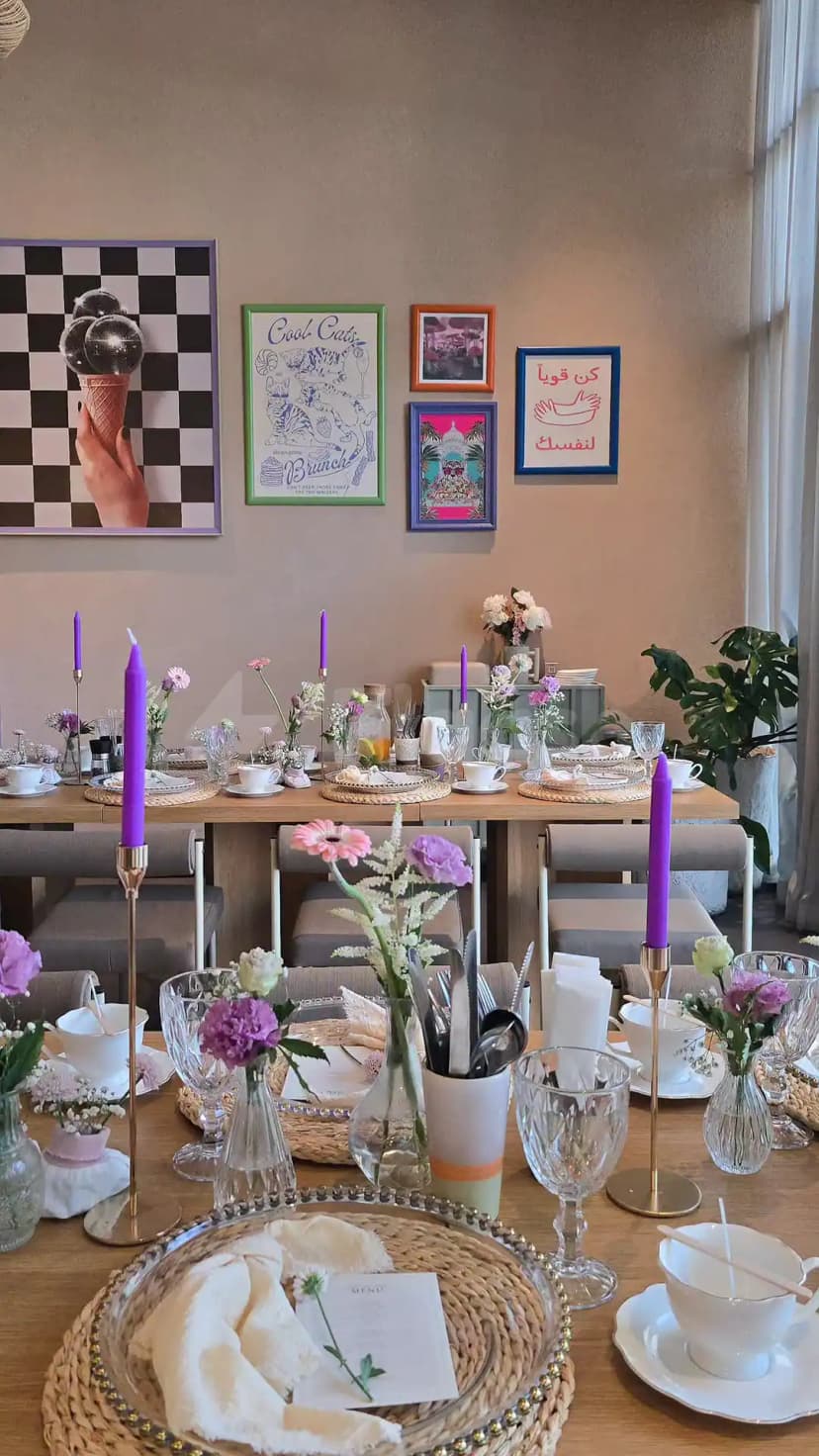 Long wooden table set for brunch at Tania's Teahouse Dubai Hills, featuring purple candles in brass holders