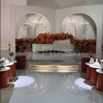 Ballroom at Hdb Sahafa in Riyadh featuring a white curved sofa, orange floral wall arrangements, and arched alcoves