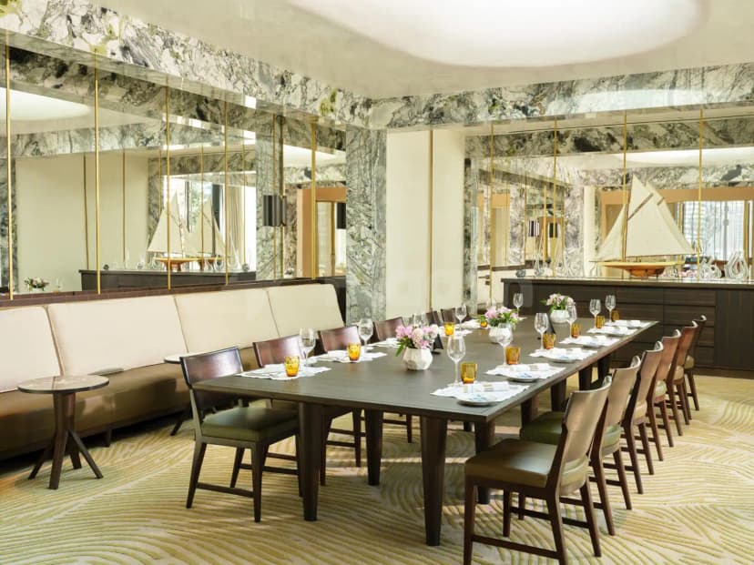 Restaurant at Riviera By Jean Imbert Dubai Business Bay featuring a long wooden dining table, marble wall panels