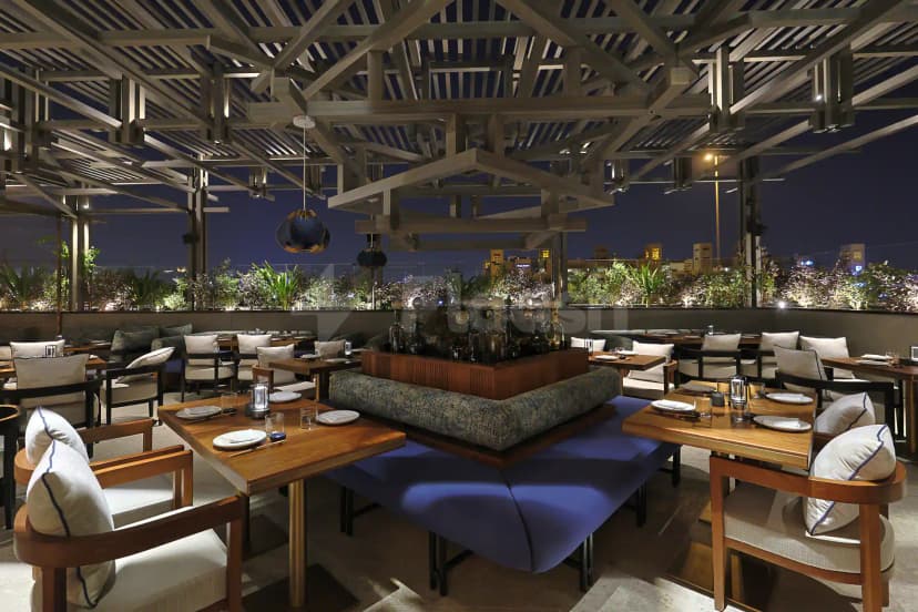 Rooftop terrace at Robata Riyadh featuring exposed wooden ceiling beams and a city skyline view at night