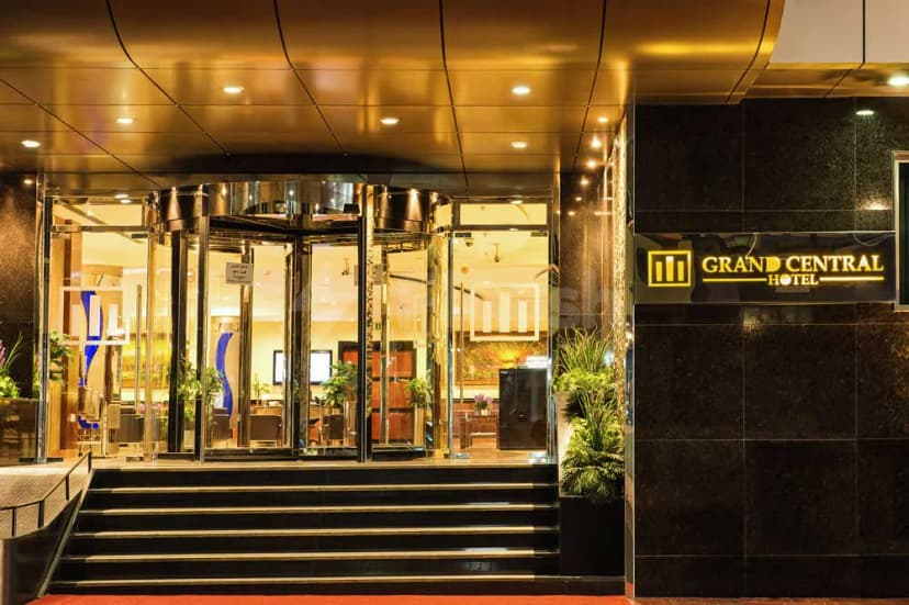 Hotel facade of Grand Central Hotel Dubai featuring a revolving glass door, black marble wall, and illuminated sign
