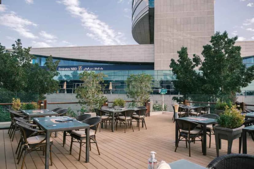 Rooftop terrace at Kimuraya Authentic Japanese Restaurant Downtown Dubai with wooden deck, wicker chairs, and Emirates NBD building