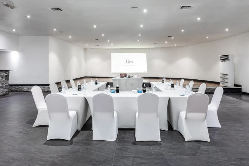 Boardroom at BM Beach Resort Ras Al Khaimah with U-shaped white table setup, projector screen displaying logo