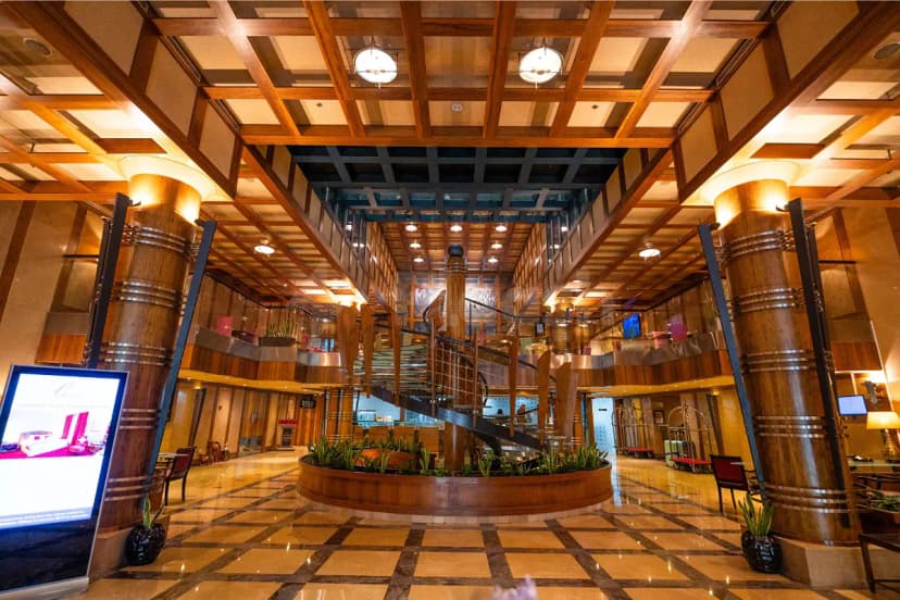 Entrance hall at Marina Byblos Hotel Dubai featuring wooden coffered ceiling and spiral staircase with glass railing
