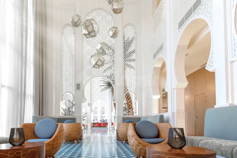 Entrance hall at Shaza Riyadh featuring white arched doorways with geometric lattice screens and hanging metallic pendant lights