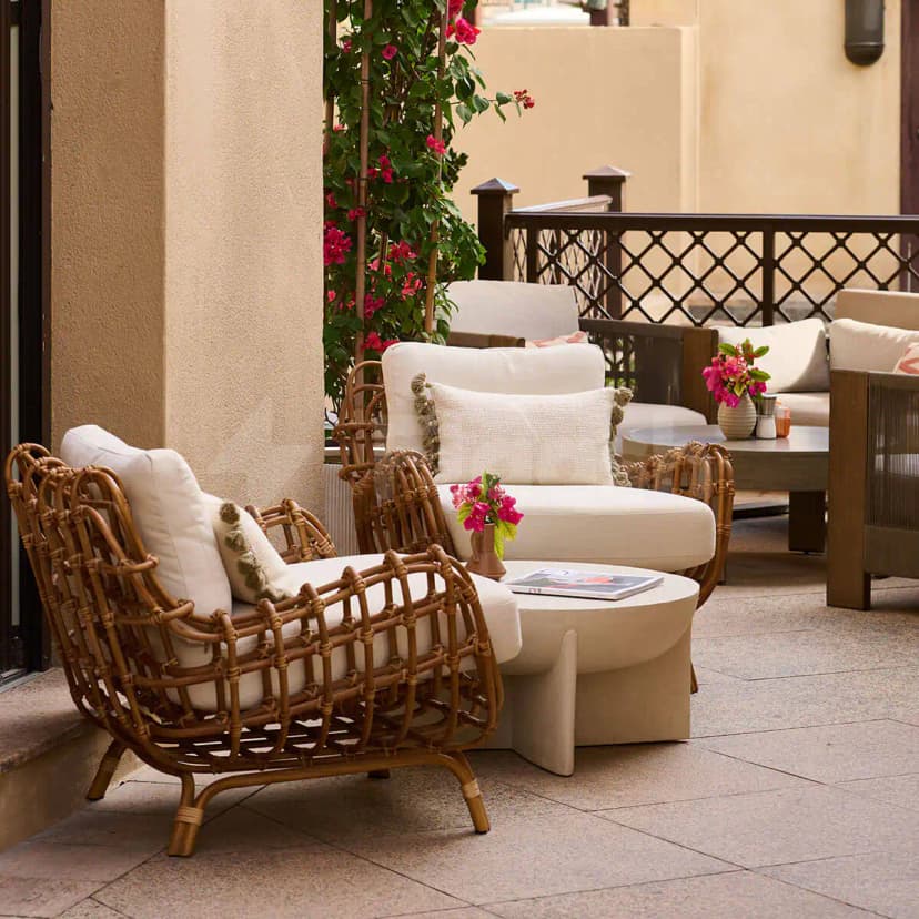 Terrace at Apricot Dubai Cafe Downtown Dubai featuring rattan armchairs with white cushions and pink bougainvillea climbing