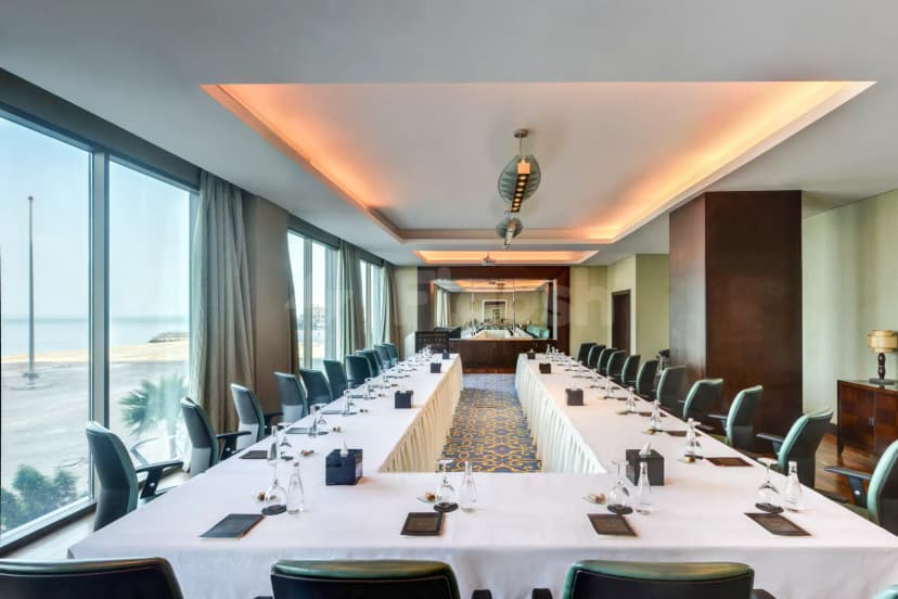 Boardroom at Sofitel Al Khobar The Corniche with long rectangular tables, white tablecloths, and floor-to-ceiling windows overlooking