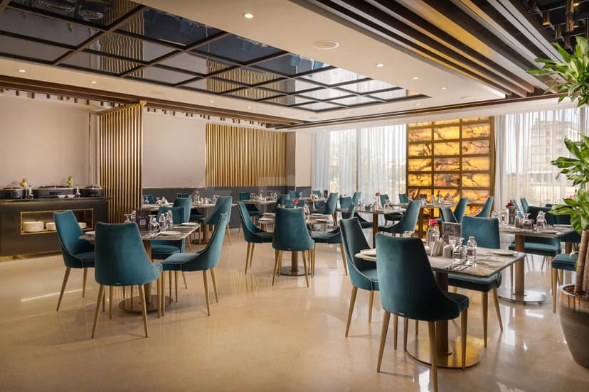 Restaurant at Joudyan King Road Jeddah by Elaf featuring round marble tables with gold bases and a backlit