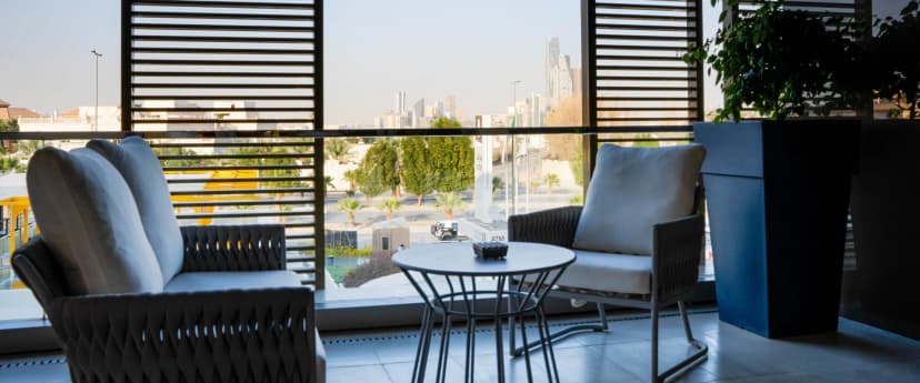 Rooftop terrace at Jareed Hotel Riyadh featuring modern wicker armchairs, a round metal table, and a city skyline