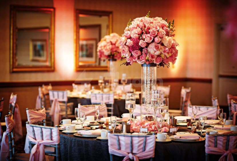 Ballroom at Crown Tower Al Jubail featuring round tables with black tablecloths and tall pink rose centerpieces