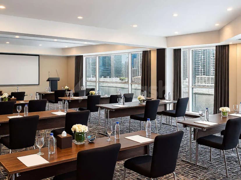 Meeting room at Gulf Court Hotel Business Bay Dubai with dark wooden tables, black chairs, and floor-to-ceiling