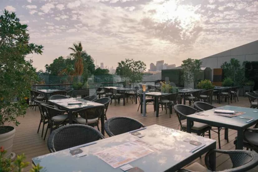Rooftop terrace at Kimuraya Authentic Japanese Restaurant Downtown Dubai with wooden deck, black wicker chairs, and city skyline