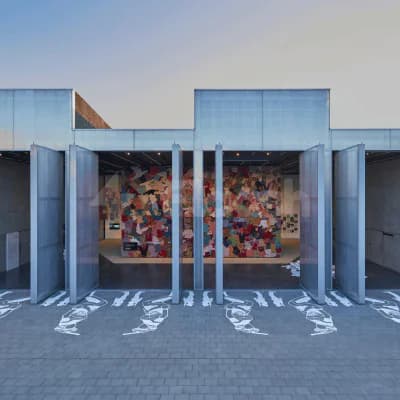 Modern entrance hall at Alserkal Avenue in Dubai featuring metal folding doors and a colourful mosaic wall visible