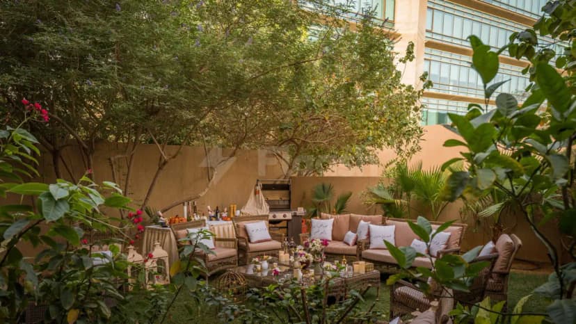Terrace at Vivienda Hada Residences in Riyadh featuring wicker seating, an outdoor grill, and lush greenery with pink