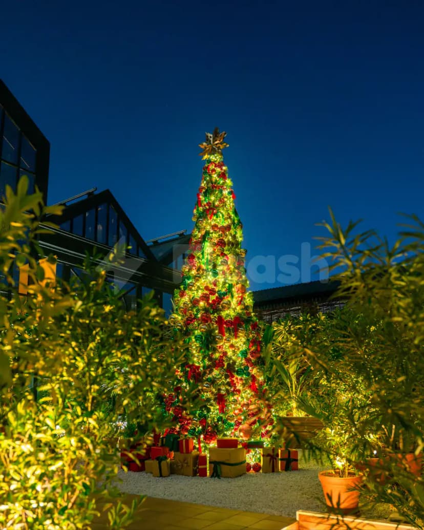 Rooftop terrace at Eugène Eugène Restaurant Dubai featuring a lit Christmas tree with ornaments and gift