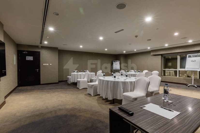 Meeting room at Vintage Grand Hotel Dubai with round tables, white chair covers, recessed ceiling lights