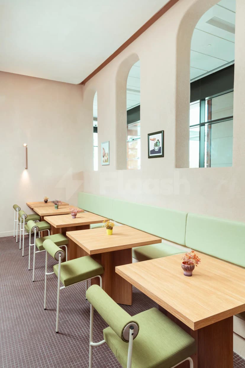 Restaurant interior at Tania's Teahouse Dubai Hills featuring green booth seating, light wooden tables, arched wall openings
