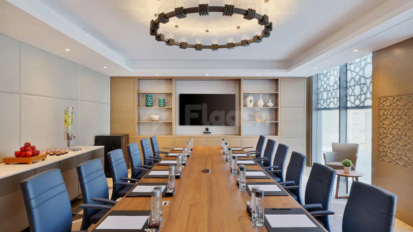 Boardroom at Courtyard by Marriott Culture Village, Dubai, featuring a long wooden table with blue leather chairs