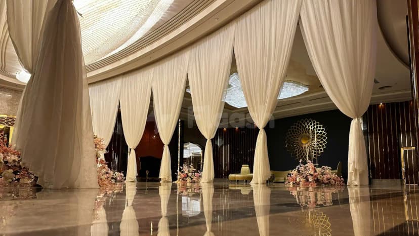 Ballroom at H Laylati Event Venue in Madinah featuring white sheer draped curtains and a polished marble floor