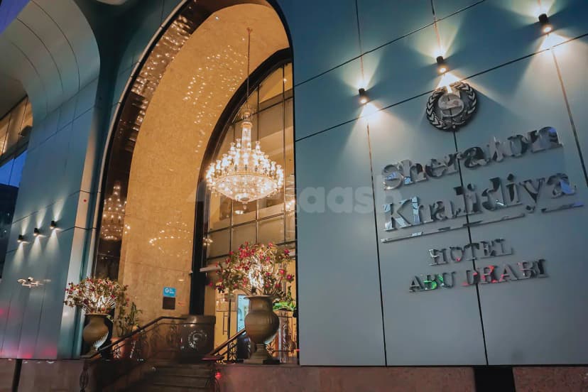 Hotel facade of Sheraton Khalidiya Abu Dhabi featuring an arched entrance with a large chandelier and metallic signage