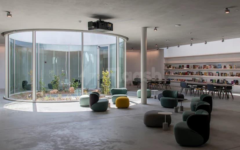 Curved glass wall enclosing an indoor garden in The Flying Saucer Sharjah meeting room with concrete floor