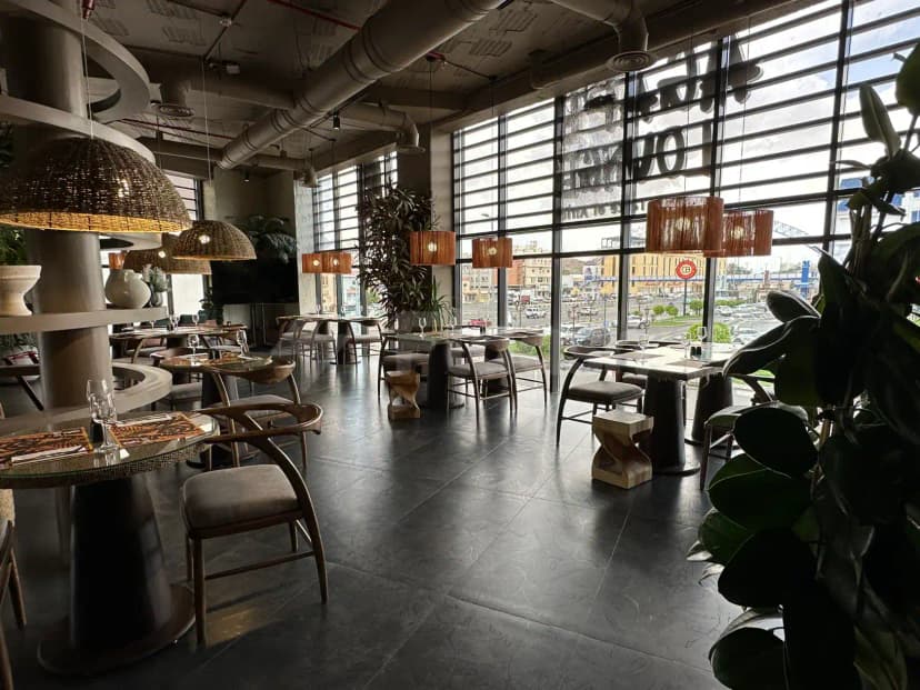 Agape Restaurant & Cafe Taif features an industrial-style dining space with exposed ductwork and large glass windows overlooking