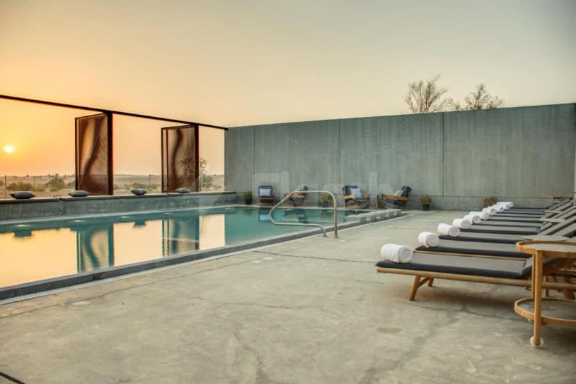 Rectangular swimming pool at Al Faya Retreat in Sharjah, featuring a concrete deck, grey wall, and decorative metal