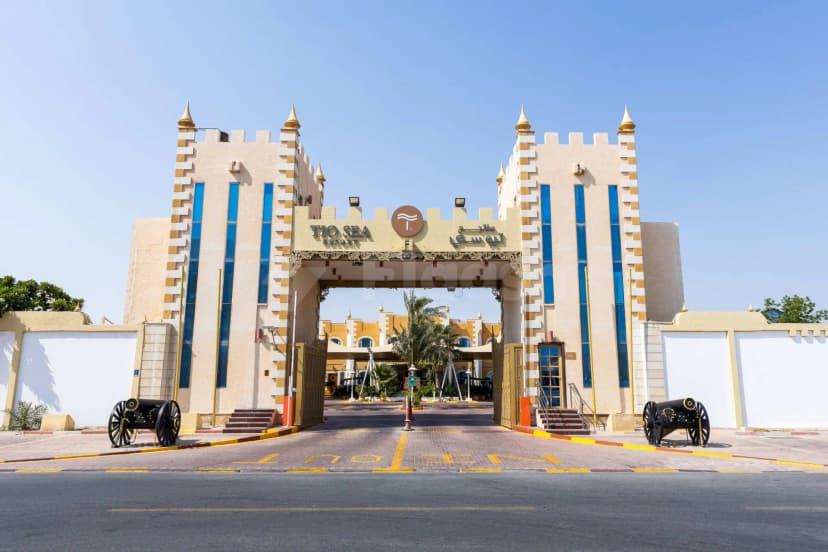 Hotel facade of Tio Sea Resort in Doha featuring an ornate archway, gold spires, and two black cannons