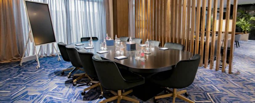 Boardroom at Jareed Hotel Riyadh featuring an oval wooden table, black velvet chairs with gold bases