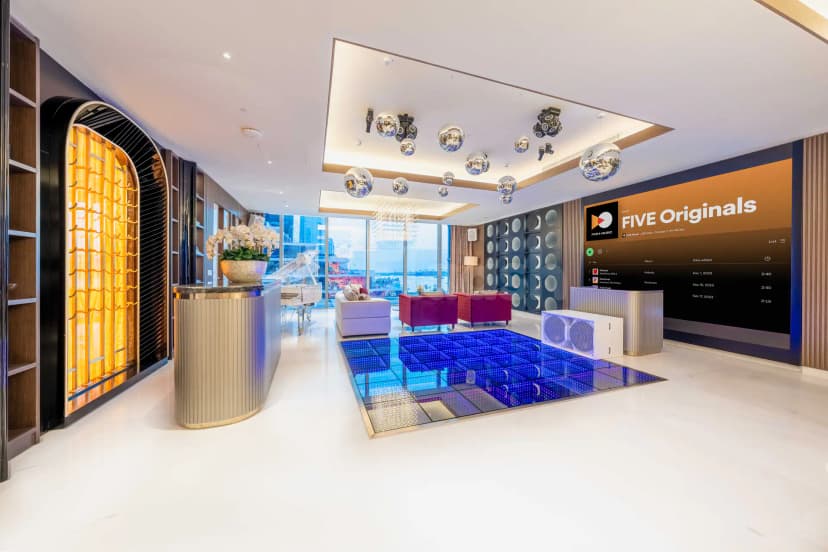 Entrance hall at Five Luxe JBR Dubai featuring a curved metallic reception counter and a blue LED dance