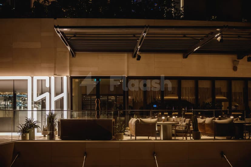 Terrace at OSH Del Mar Restaurant Dubai Marina featuring glass railing, modern lounge seating, and illuminated signage