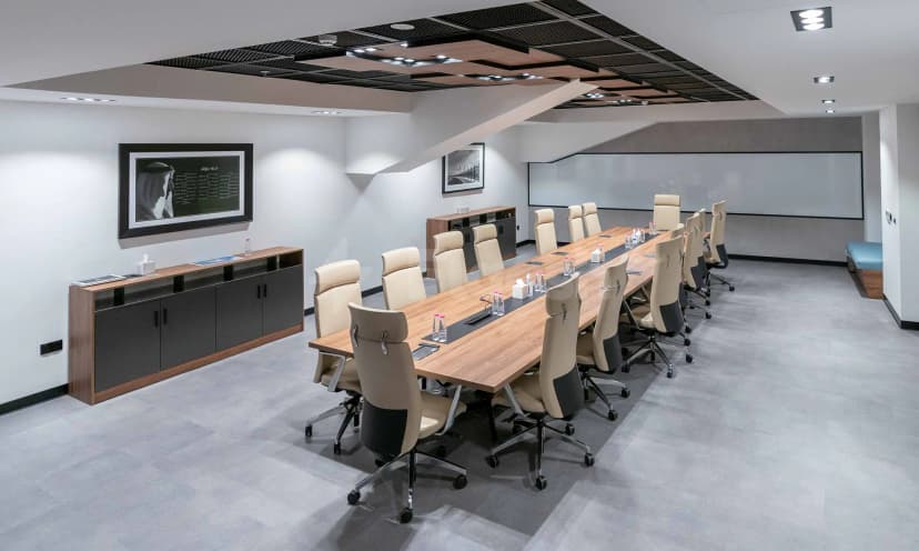 Boardroom at AlMajaz Amphitheatre Sharjah featuring a long wooden table, beige leather chairs, and an angular ceiling grid