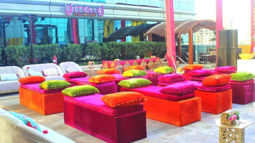 Rooftop terrace at Vintage Grand Hotel Dubai featuring low velvet ottomans with cushions and a wooden pergola