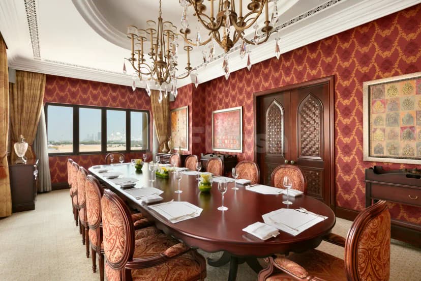 Boardroom at Shangri-La Qaryat Al Beri Abu Dhabi featuring a long wooden table, ornate chairs, red patterned wallpaper