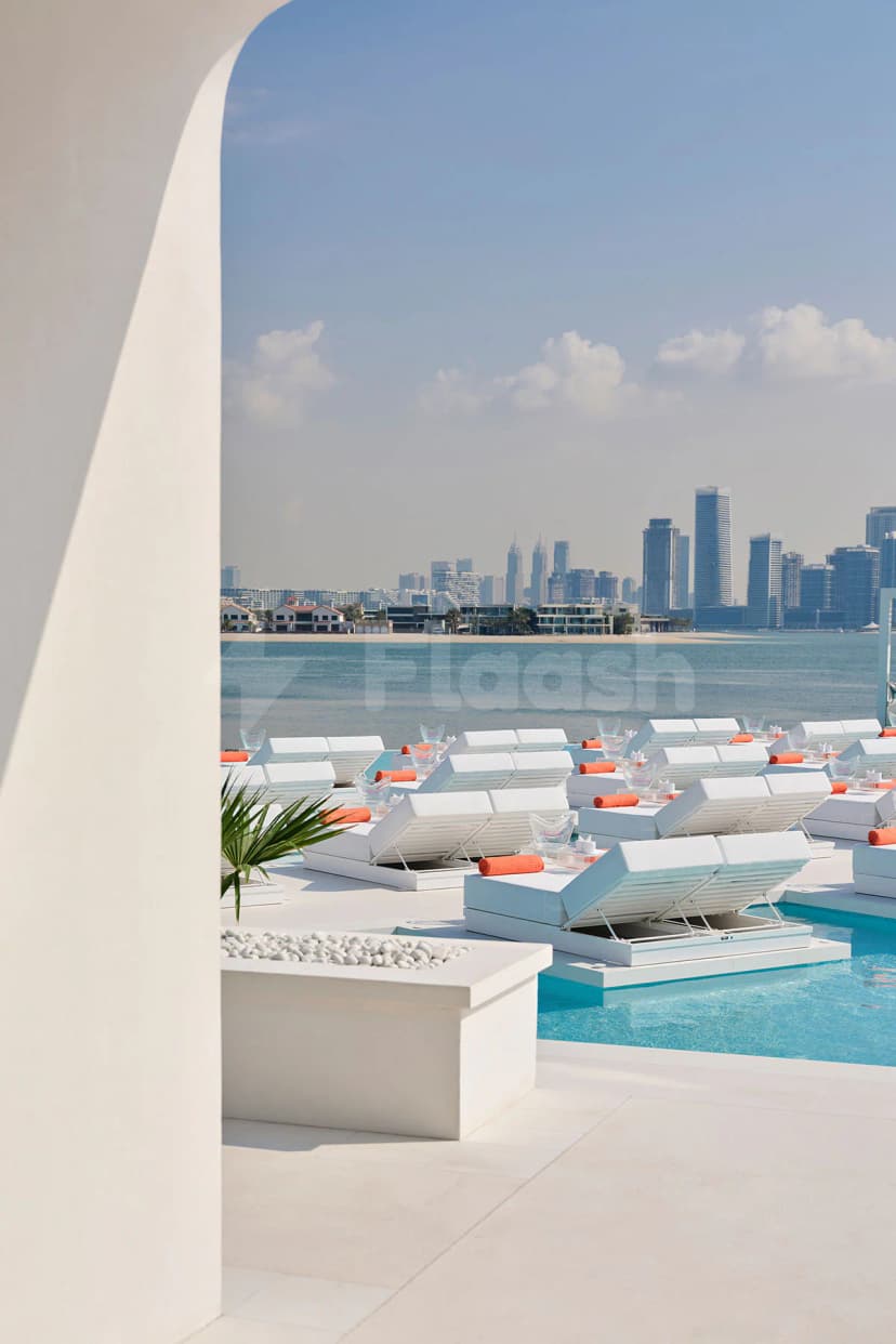 Rooftop terrace at BCH CLB in Dubai featuring white lounge chairs with orange towels and a turquoise pool