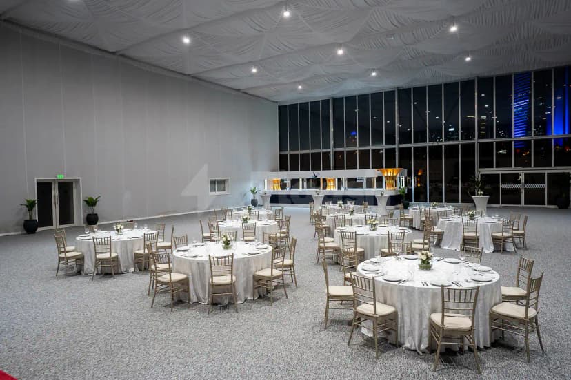 Ballroom at Emirates Golf Club in Dubai set with round tables, gold chiavari chairs, and draped white ceiling