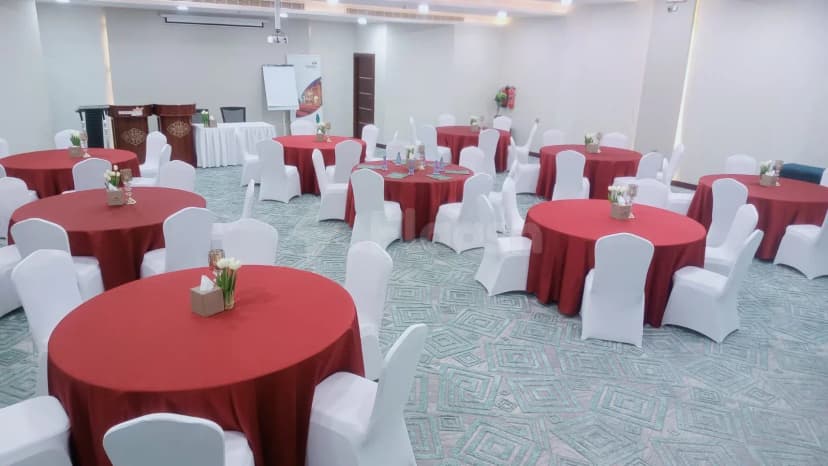 Ballroom at Garden Plaza Al Hafouf in Al Hofuf with round tables, red tablecloths, white chair covers