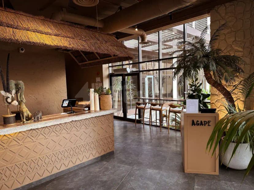 Entrance hall of Agape Restaurant & Cafe in Taif featuring a reception desk with geometric patterned panel and thatched