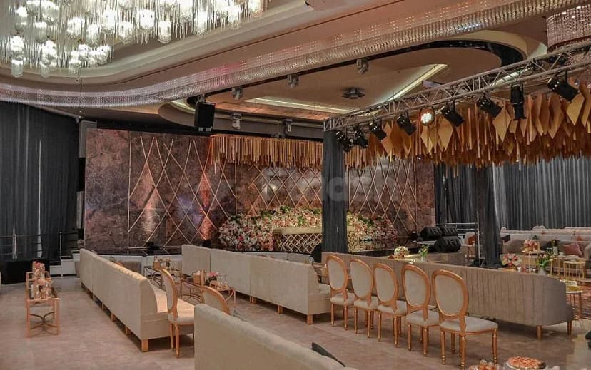 Ballroom at H Laylati Event Venue in Madinah featuring a marble-patterned backdrop wall and crystal chandeliers with gold