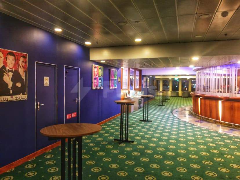 Restaurant at Theatre by QE2 in Dubai featuring a green patterned carpet, blue walls, and a curved wooden