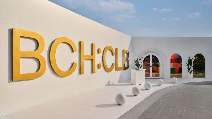 Entrance hall of BCH CLB in Dubai featuring a white stucco wall with large gold letters and arched