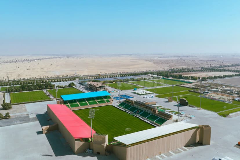 The Sevens Stadium in Dubai features a central football pitch with green seating and a red canopy, set
