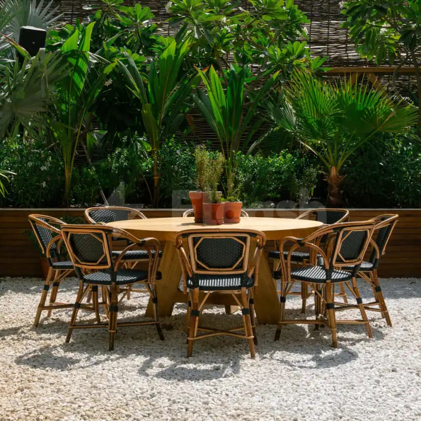 Terrace at Eugène Eugène Restaurant Dubai featuring a round wooden table, rattan chairs with black woven