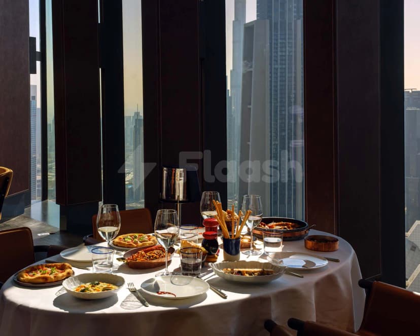 Restaurant at ICD Brookfield Place Dubai featuring a round dining table with white tablecloth and large floor-to-ceiling